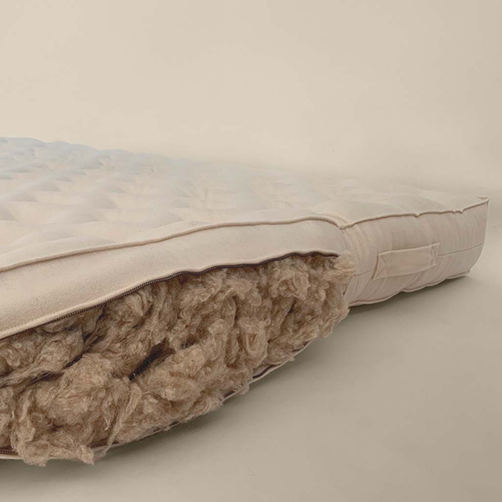 Close-up of natural wool filling inside a tufted mattress with side zipper open