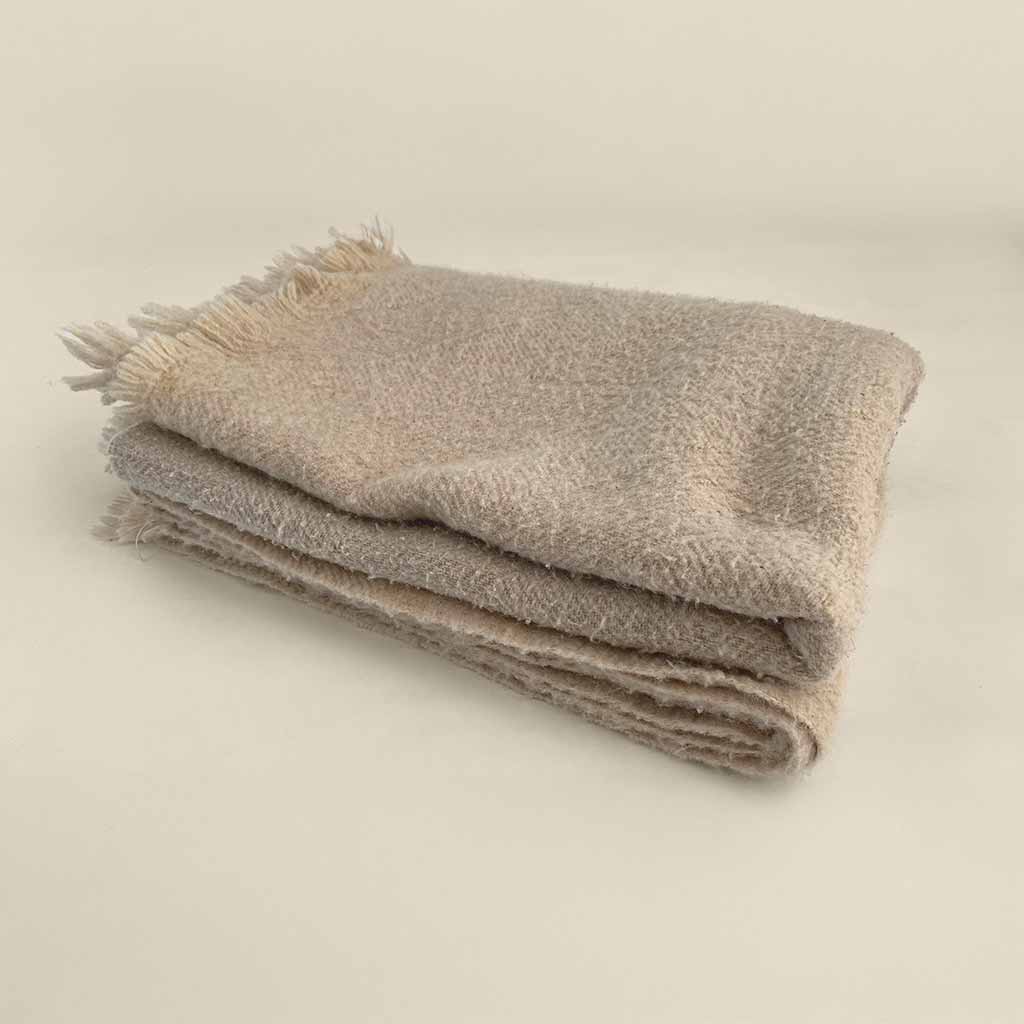 Folded wool blanket with soft texture and fringed edge, made from natural fibers for cozy, breathable warmth