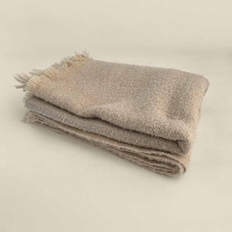 Folded wool blanket with soft texture and fringed edge, made from natural fibers for cozy, breathable warmth