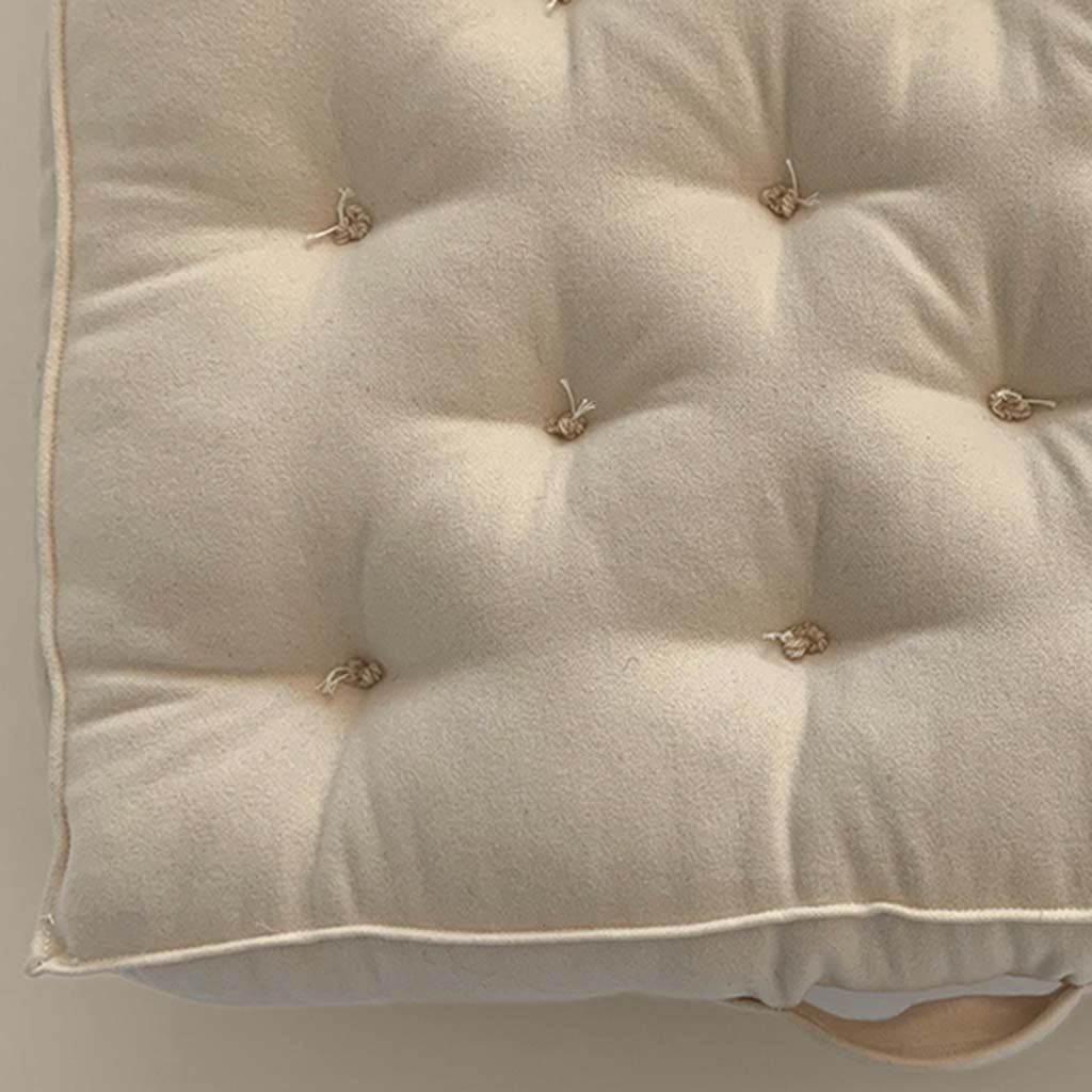 Detail of hand-tufted wool mattress surface with natural knots and soft fabric cover