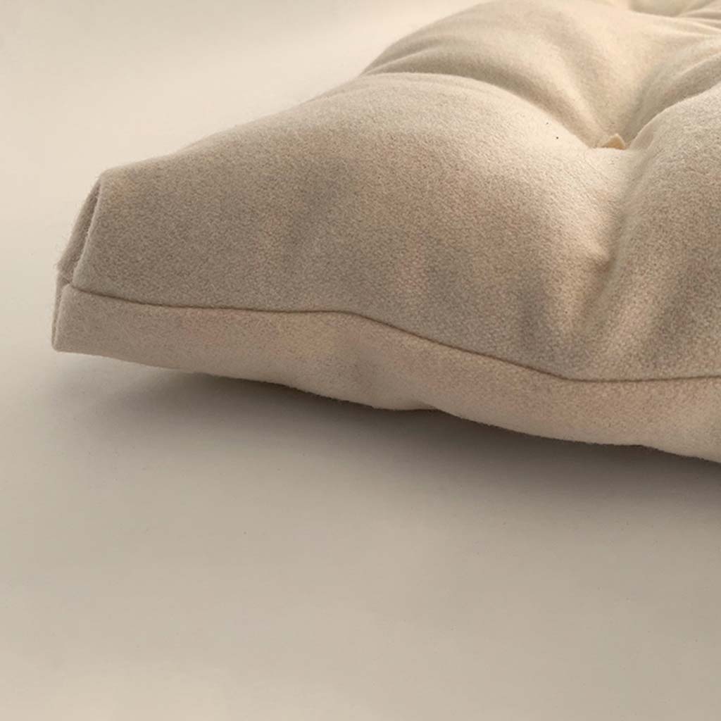Side view of a wool mattress topper showing its plush thickness, natural fabric texture, and hand-tufted detail