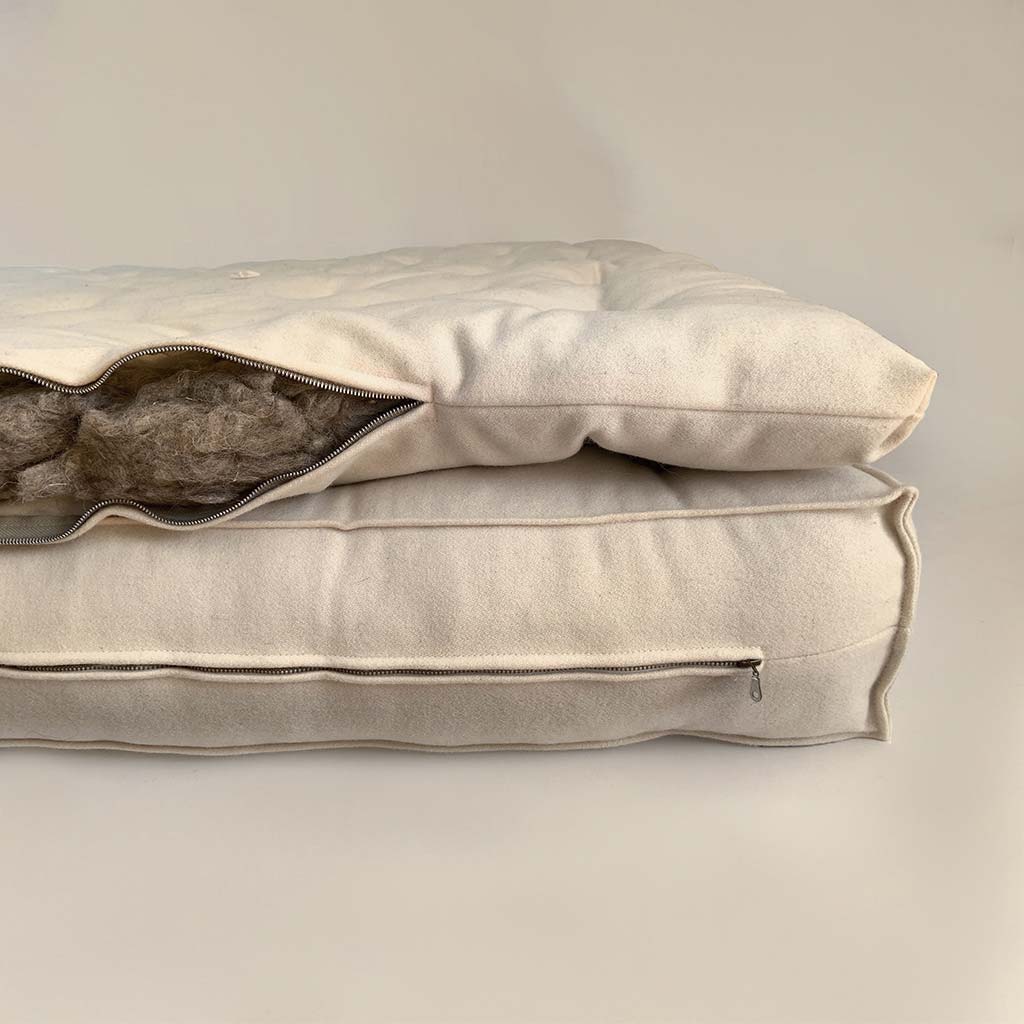 Wool mattress topper with certified wool filling, shown open to reveal the interior, placed on a natural wool mattress