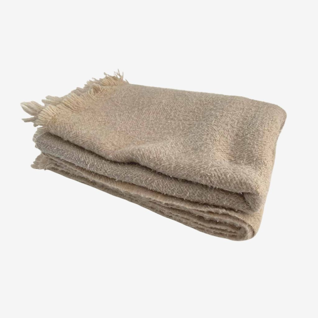 Folded wool blanket with soft texture and fringed edge, made from natural fibers for cozy, breathable warmth.
