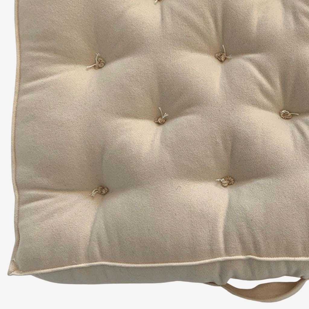 Detail of hand-tufted wool mattress surface with natural knots and soft fabric cover.