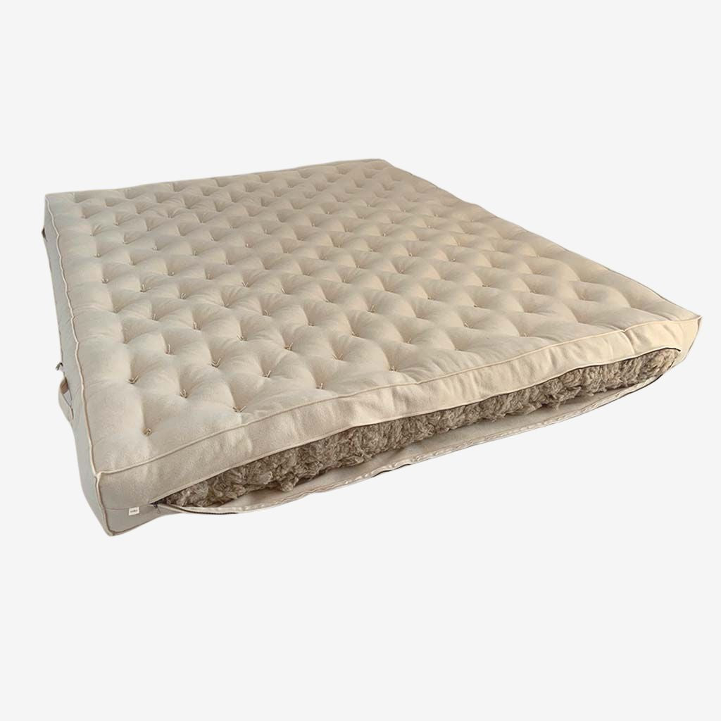 All-natural wool mattress with hand-tufted surface and visible wool filling cutaway.