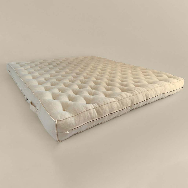 Natural wool mattress with tufted surface and visible side profile showing its full thickness