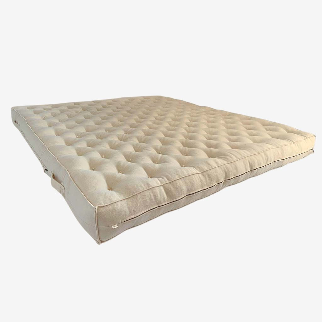 Natural wool mattress with tufted surface and visible side profile showing its full thickness.