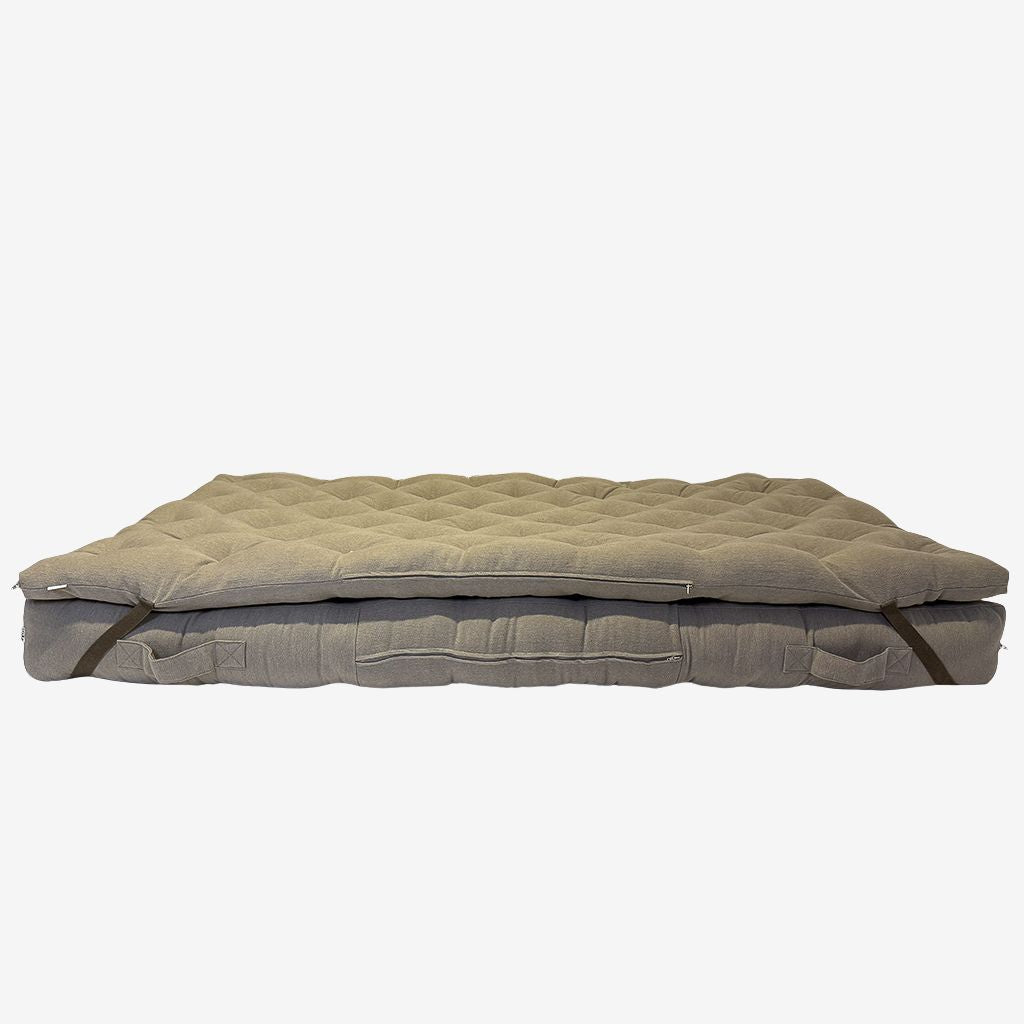 Brown linen wool mattress topper layered on wool mattress – side view showing straps, tufting, and zipper.